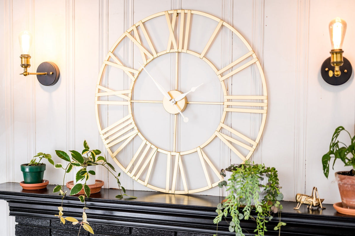 Hermle Anya wall clock above a dark console with plants and wall lights