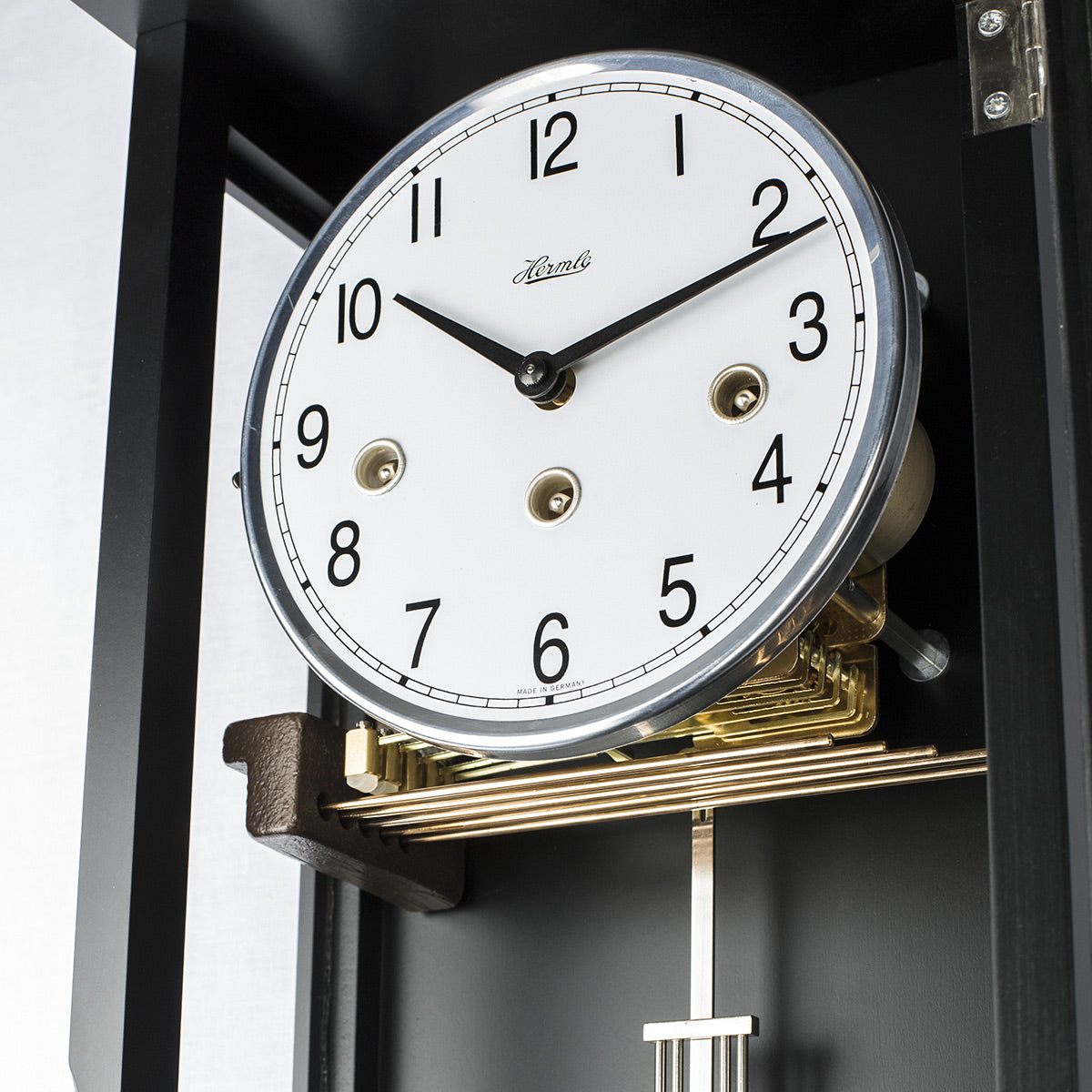 Walnut wood wall clock with pendulum and gold highlights on a white background
