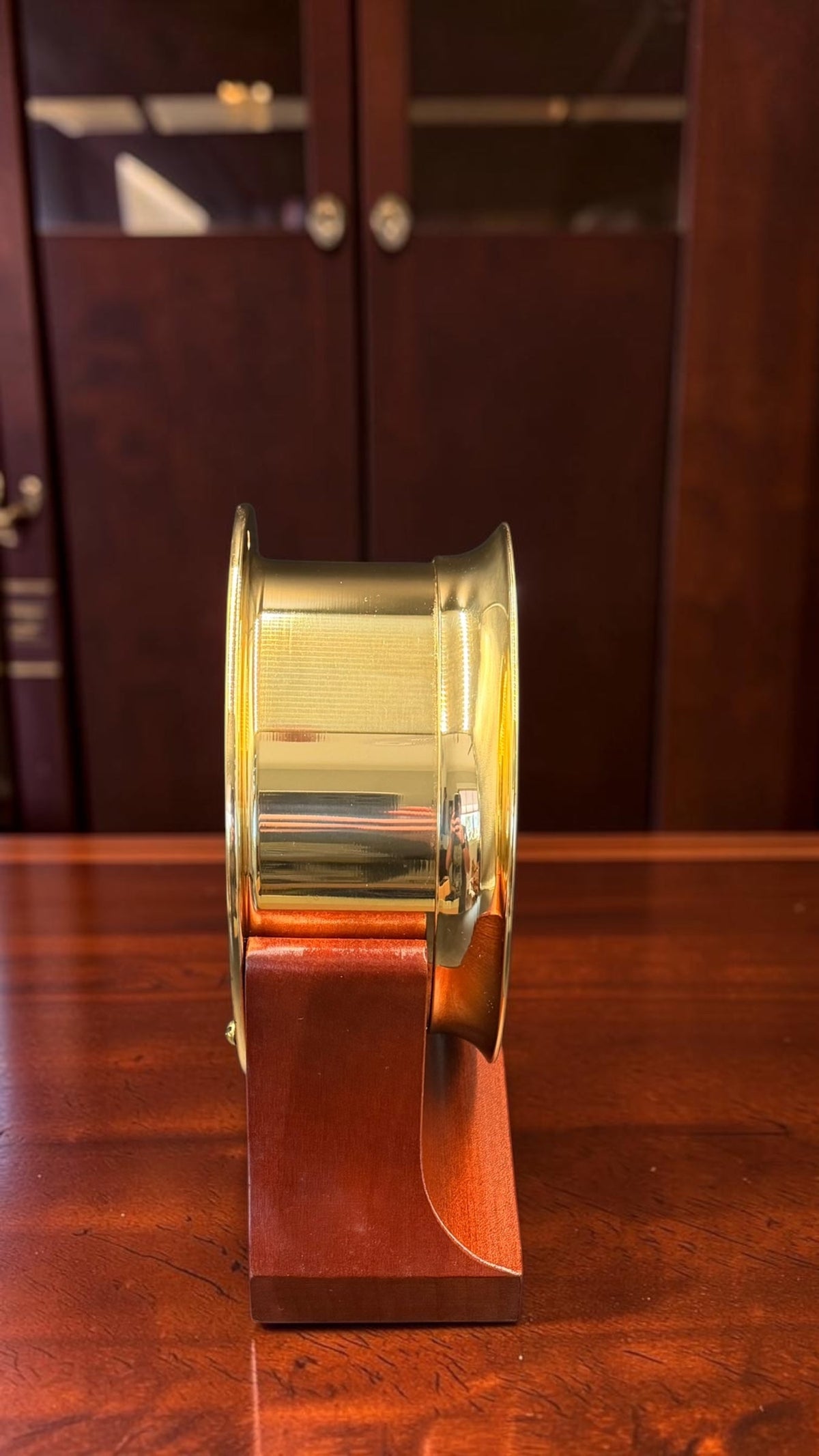 Left profile of pristine Chelsea Newport brass nautical clock on wooden stand