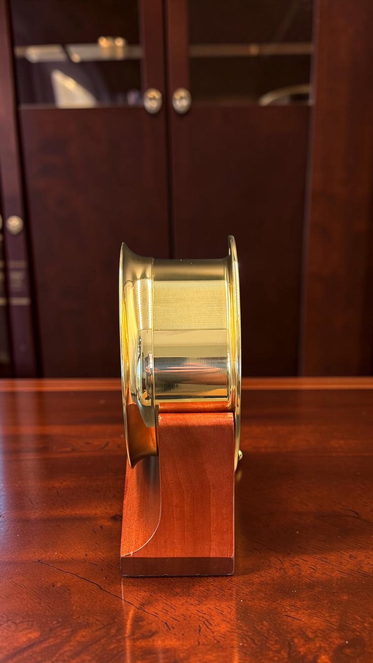 Right profile of Chelsea Newport clock showing brilliant mirror-polished brass case and wood cradle