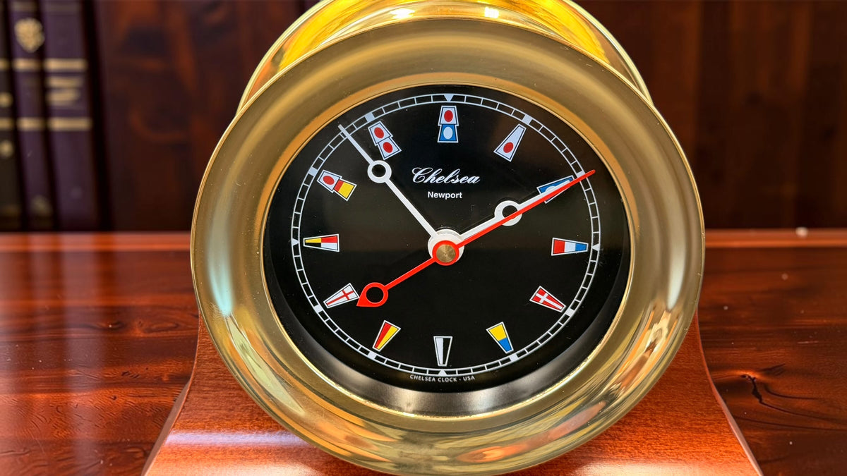 Chelsea Newport clock front close-up showing brass bezel and black nautical flag dial