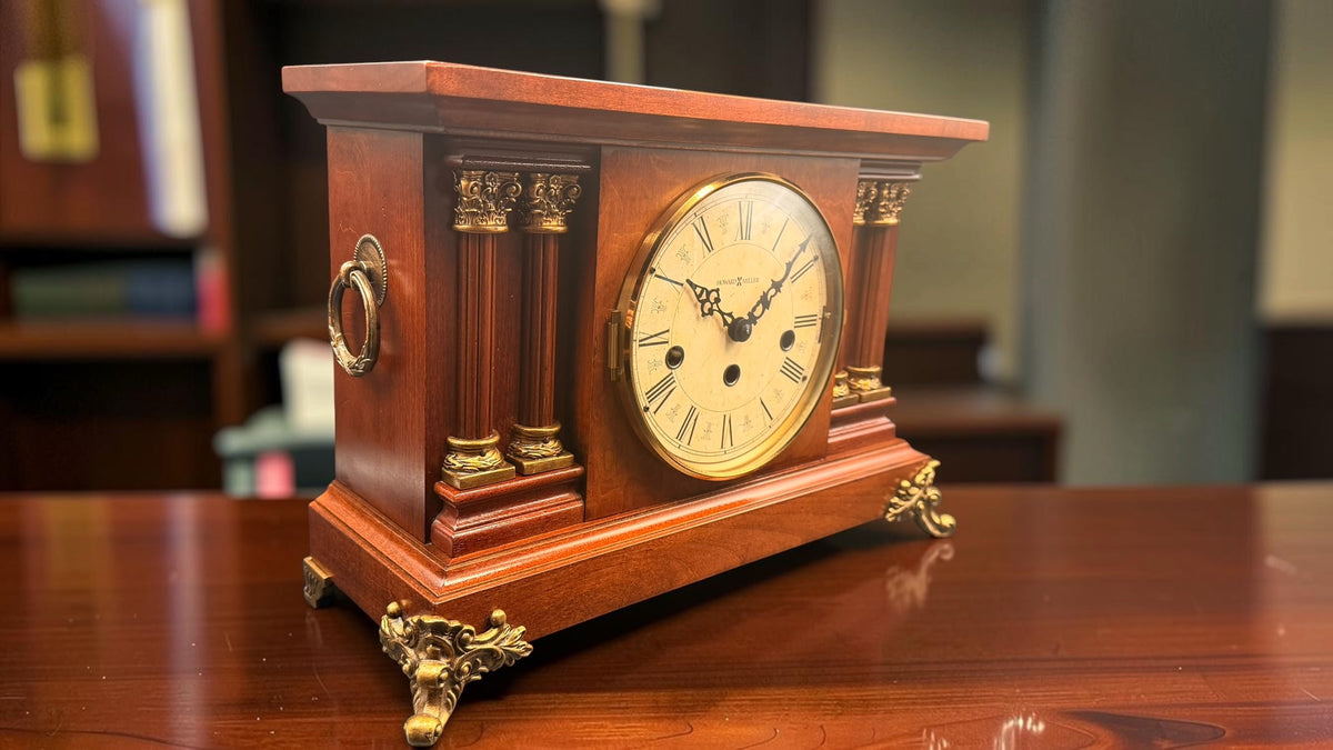 Angled view of Howard Miller Circa vintage mantel clock showing gold-tone classical pillars and feet