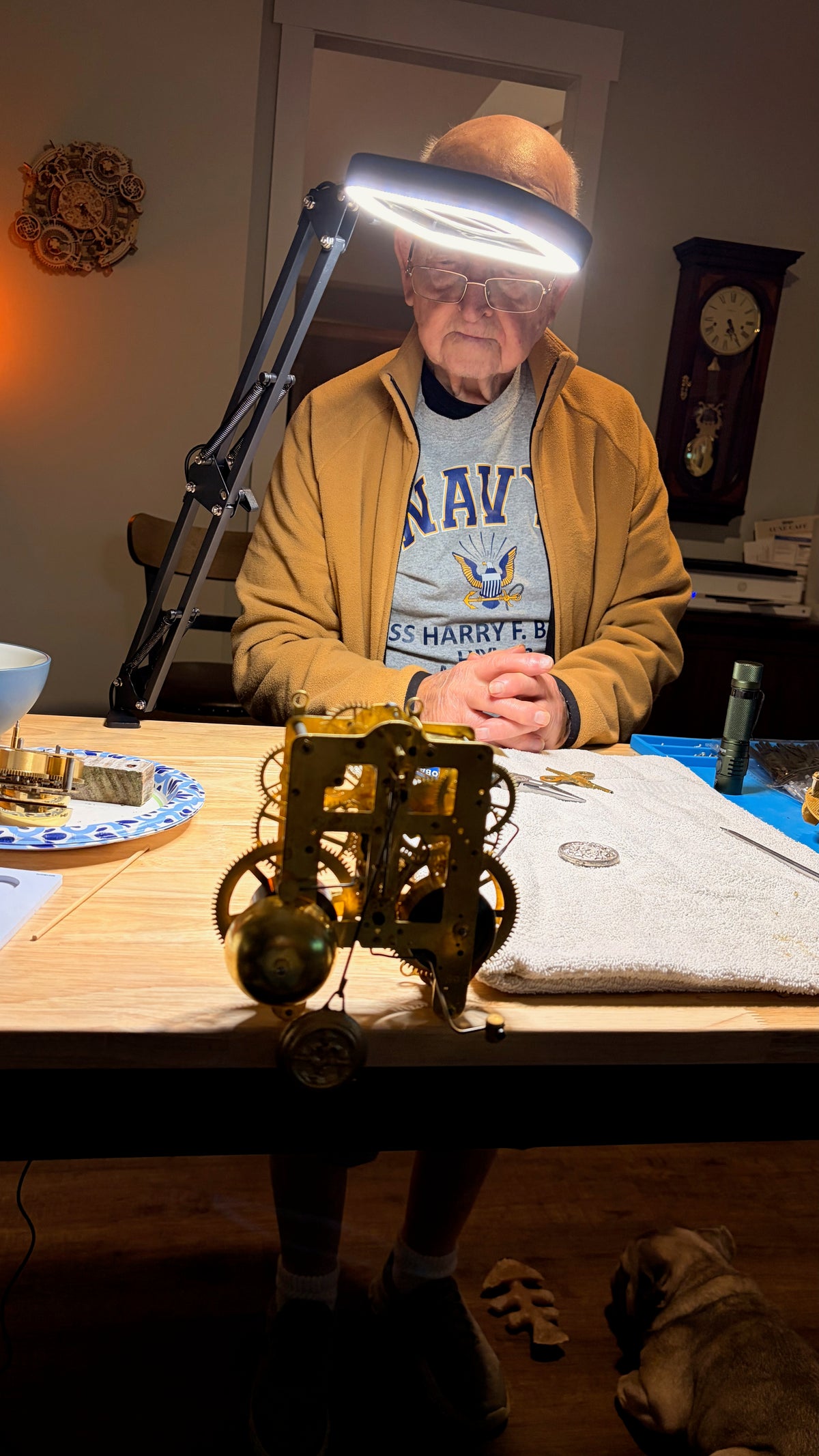 Andy’s dad watching at the worktable with a mechanical clock movement in front of him.
