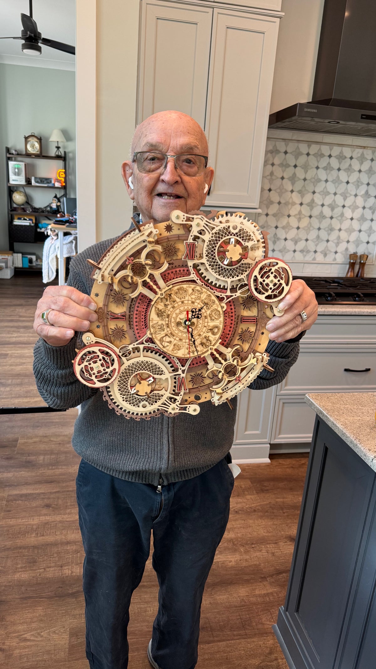 Andy’s dad holding a finished wooden clock model in 2024.