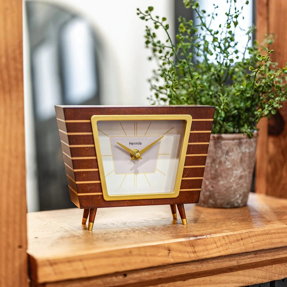 Hermle Finn wooden mantel clock on a console beside a green plant